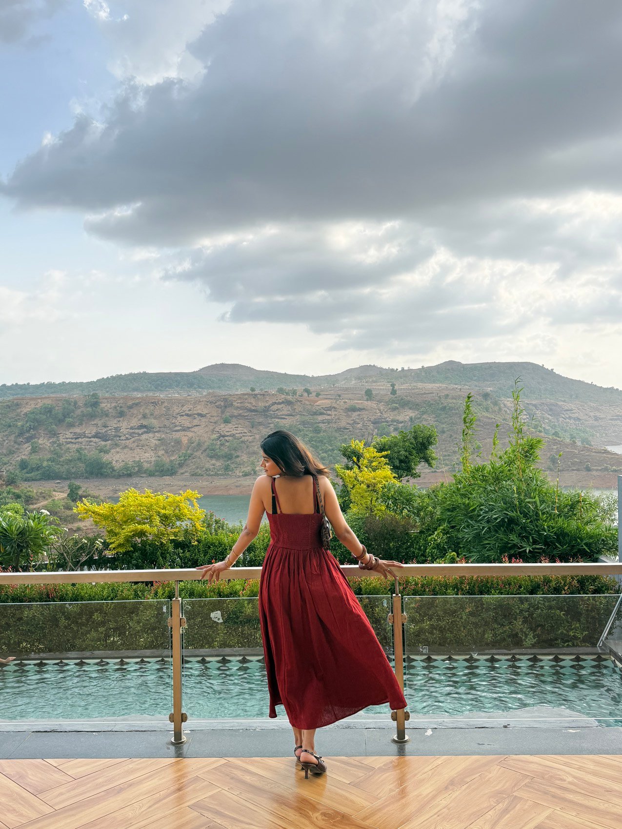 Anushka Sonawane in a rust maxi dress overlooking a hillside pool